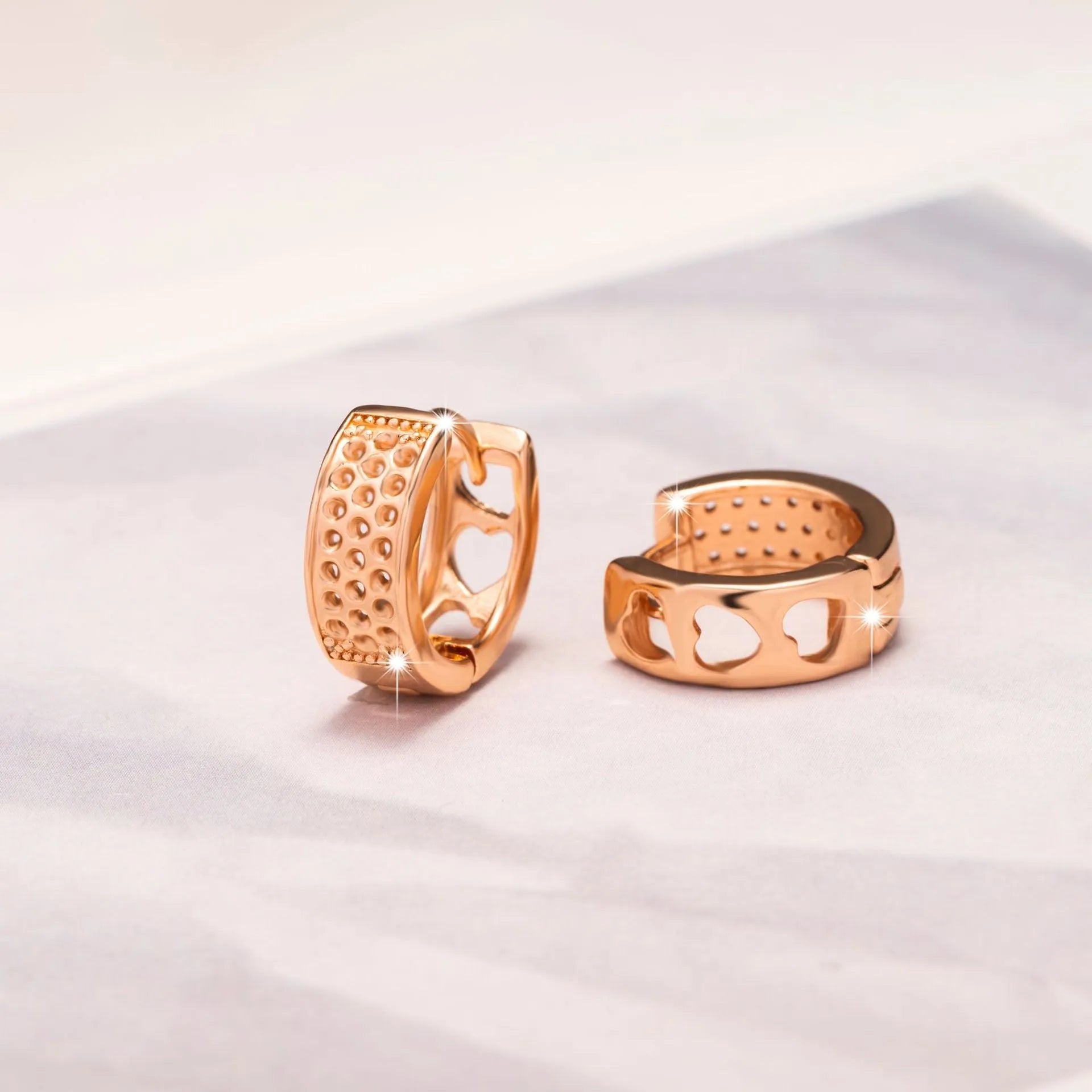 Rose gold coloured earrings with three hollow heart shapes arranged in circular pattern