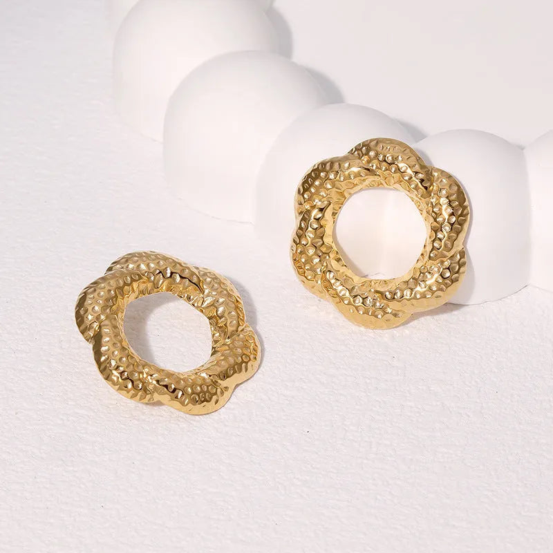 Stainless steel round stud earrings in gold and steel colours on a neutral background