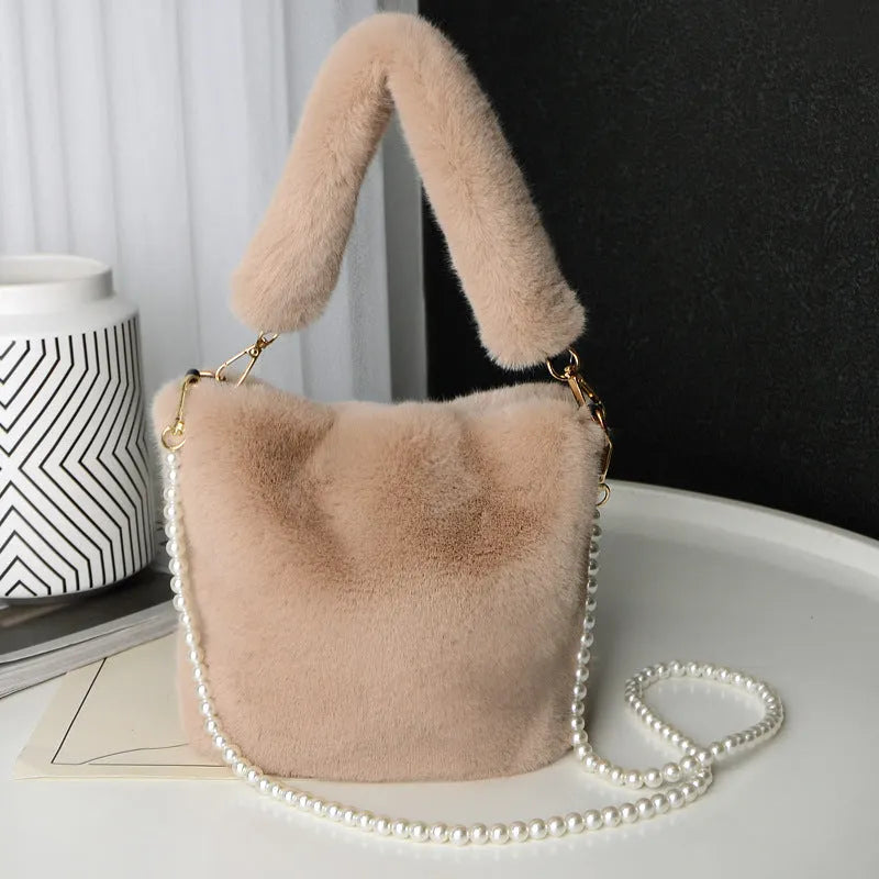 Plush bucket bag with gold-toned pearl chain on a beige background