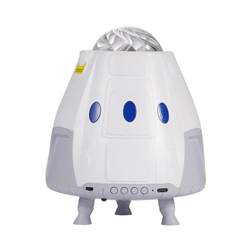 Tall white space capsule galaxy projection lamp with USB cable and remote control on a table.