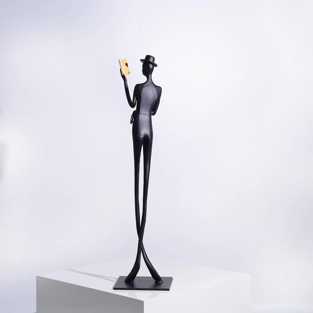 Black metal sculpture of a woman reading, modern aluminium desktop ornament.
