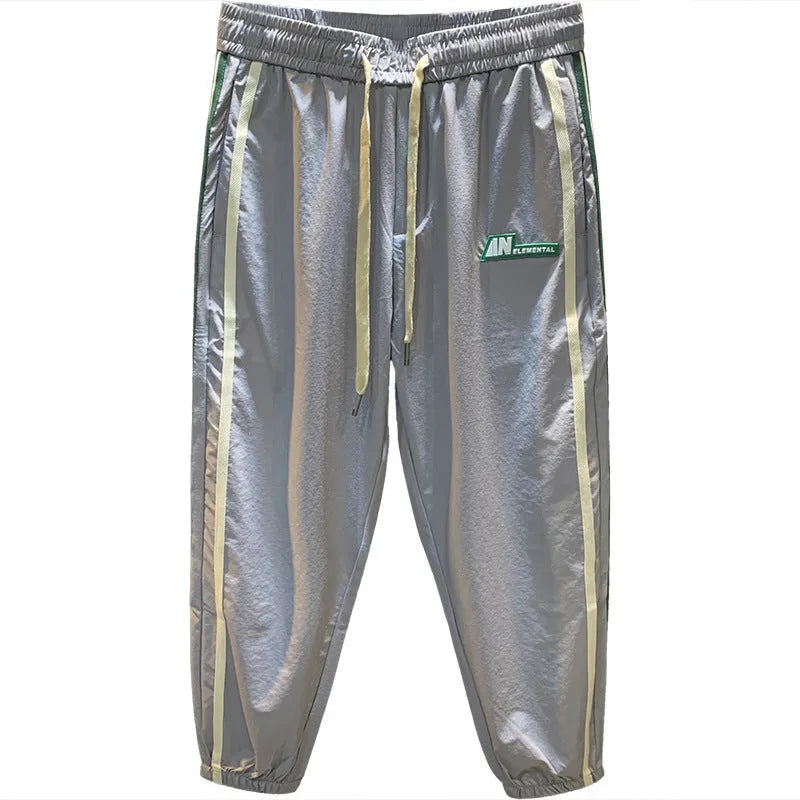 Men's black cotton harem-style casual trousers with a tapered leg on a grey background.