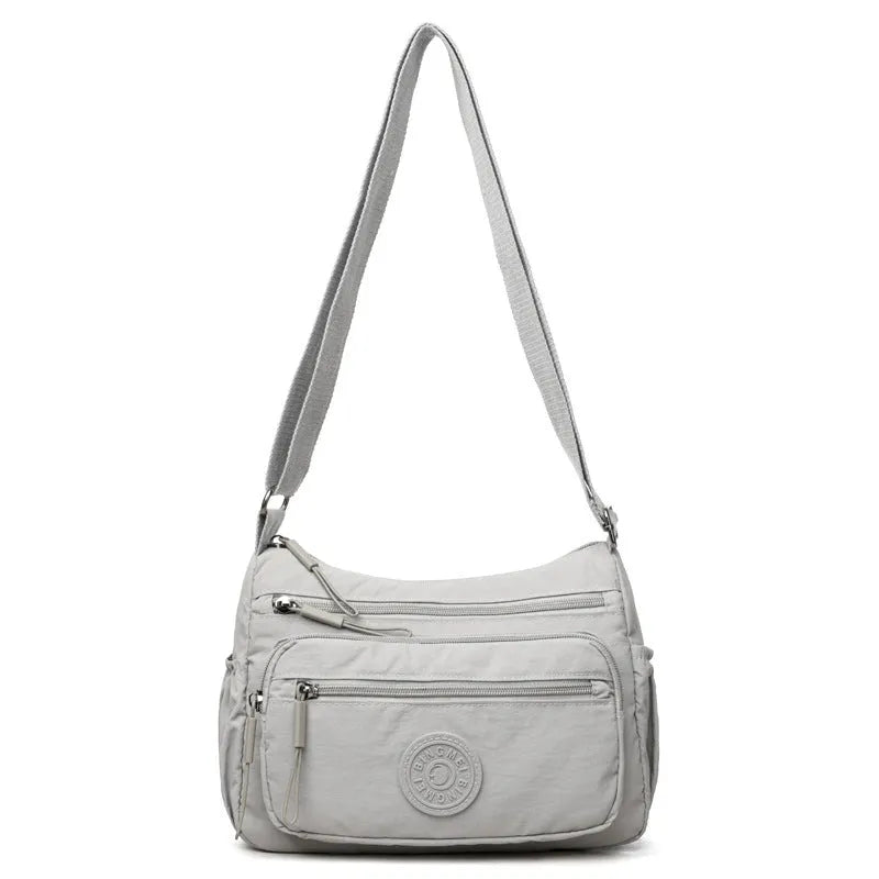 Water-repellent nylon crossbody cloth bag showing internal zipper compartments and shoulder strap