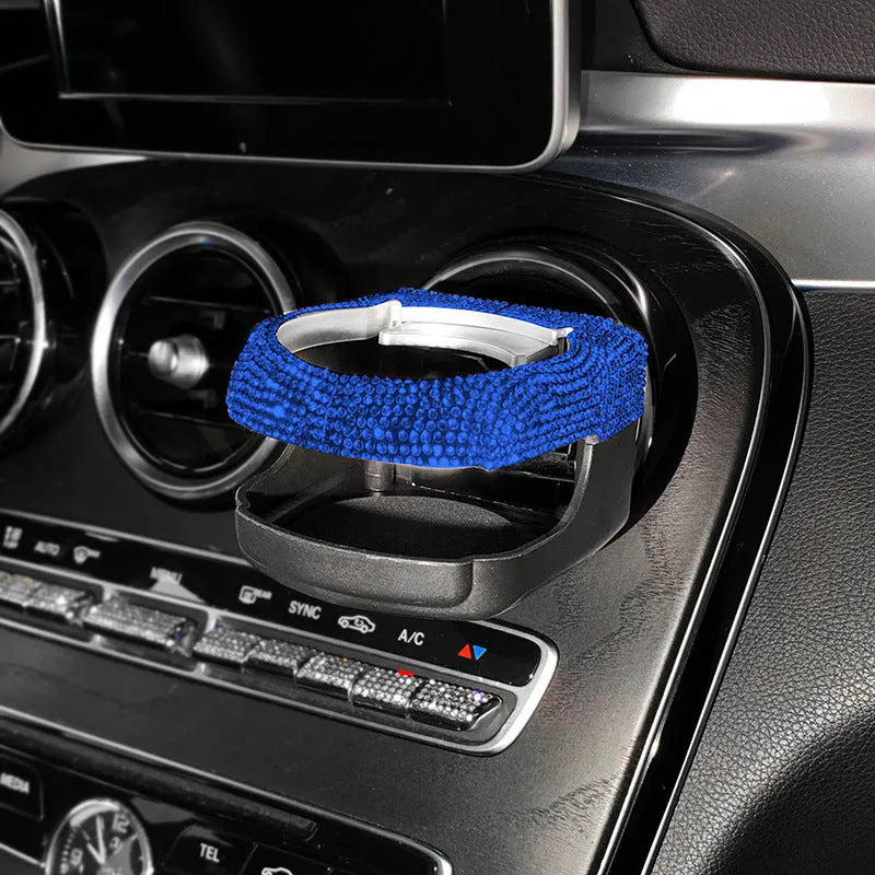 White diamond rhinestone car air vent cup holder bracket on a grey car dashboard.