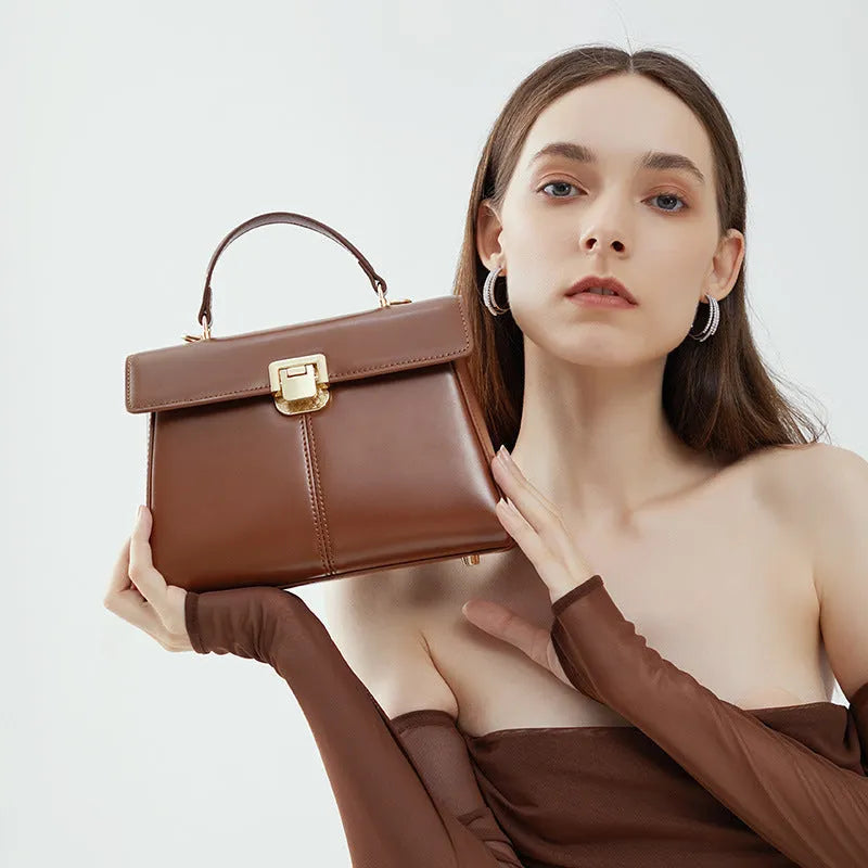 Women's black leather shoulder bag with clasp closure and adjustable strap showing interior organisation