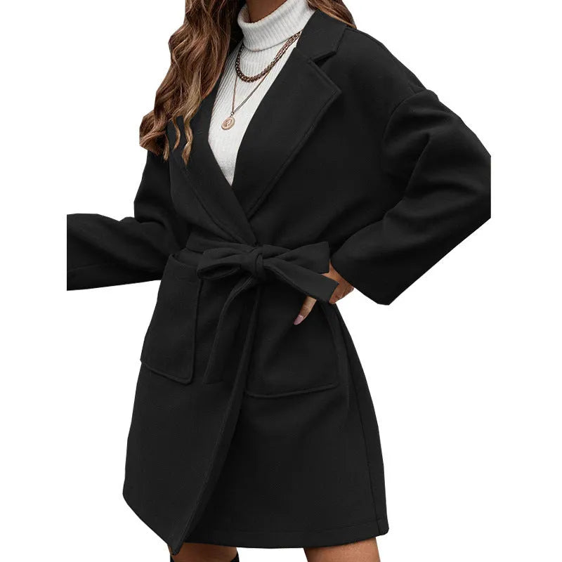 Long sleeve belted coat in thick polyester fabric shown in a loose fit on a model.