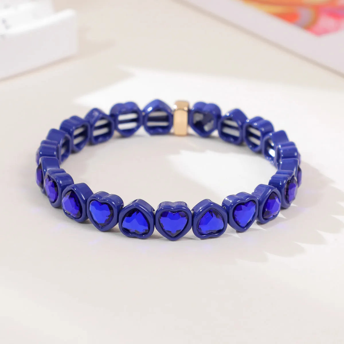 Colourful enamel finish alloy heart charm on a black stretch bracelet band.