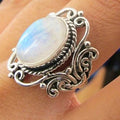 Vintage alloy ring with flower-shaped artificial moonstone gemstone on a neutral background showing side view