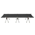 Lightweight portable folding bed set up outdoors in khaki colour with metal frame.