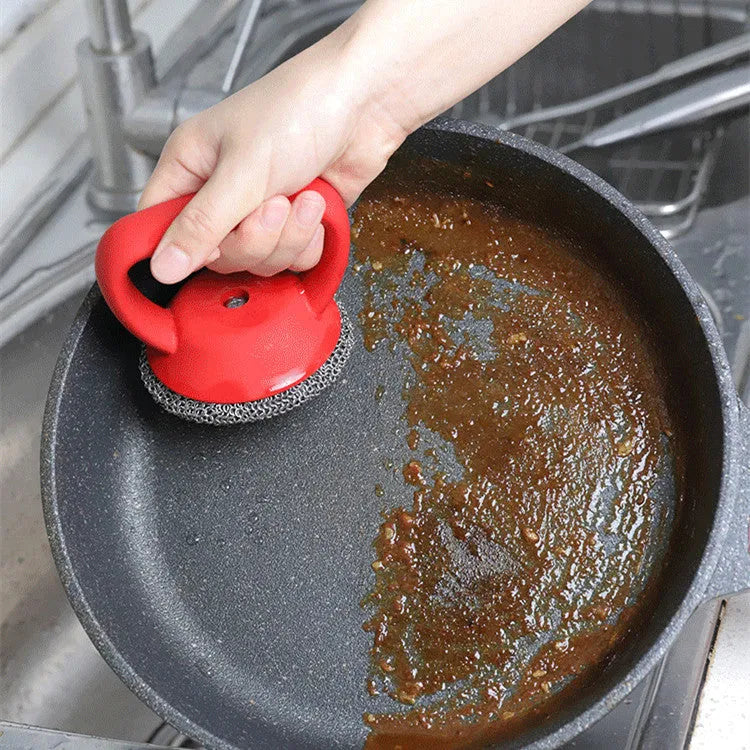 Round 316 stainless steel chainmail scrubber with red silicone handle on cast iron skillet