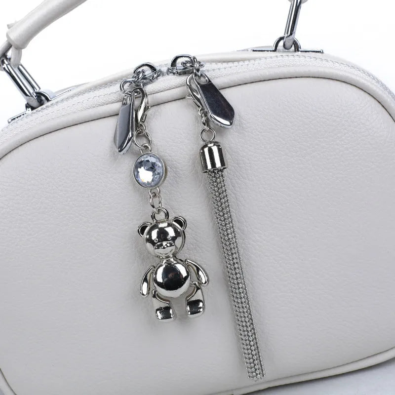 Women's small oval crossbody bag in PU with stitching detail and double straps, shown in multiple colours.