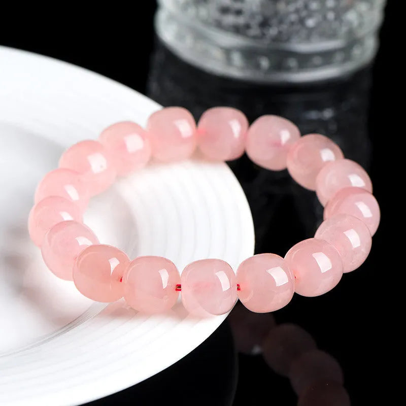 Pink crystal barrel-shaped bead bracelet on a wrist, showing geometric beads and polished finish.