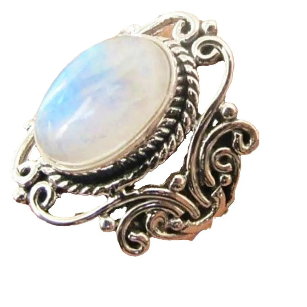 Vintage alloy ring with flower-shaped artificial moonstone gemstone on a neutral background showing side view