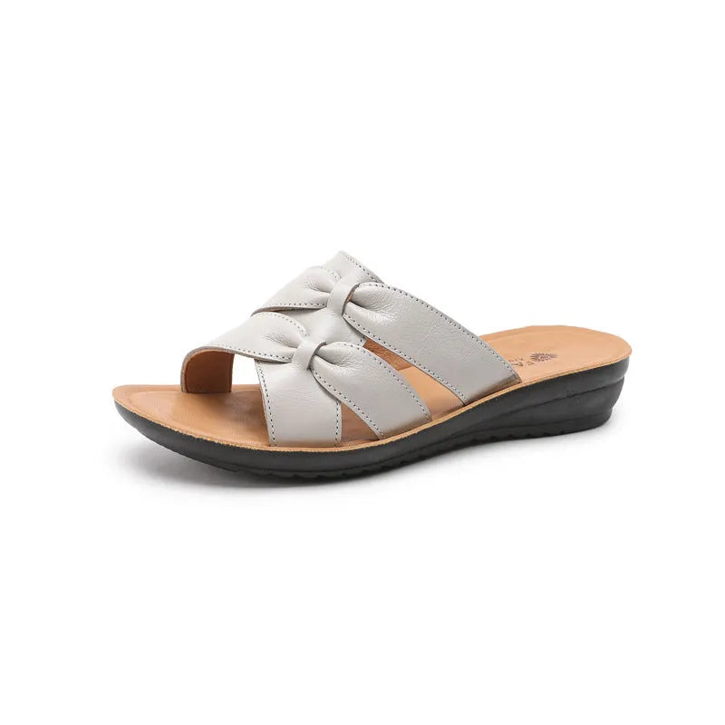 Women's beige cowhide leather slippers with a non-slip sole shown on a white background.