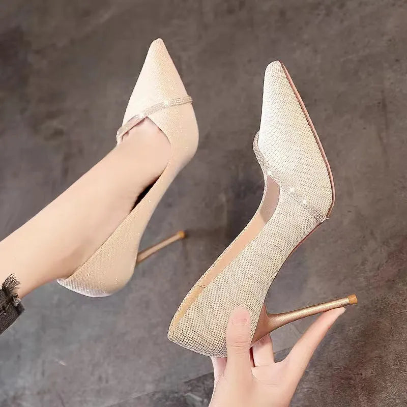 Gold and black women's pointed toe stiletto high heels on a plain background.