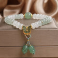 Green crystal abacus bead bracelet with a retro butterfly charm and tassels on a white background.
