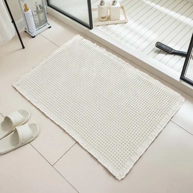 A square, checkered-pattern bathroom carpet in a choice of colours on a tiled floor.