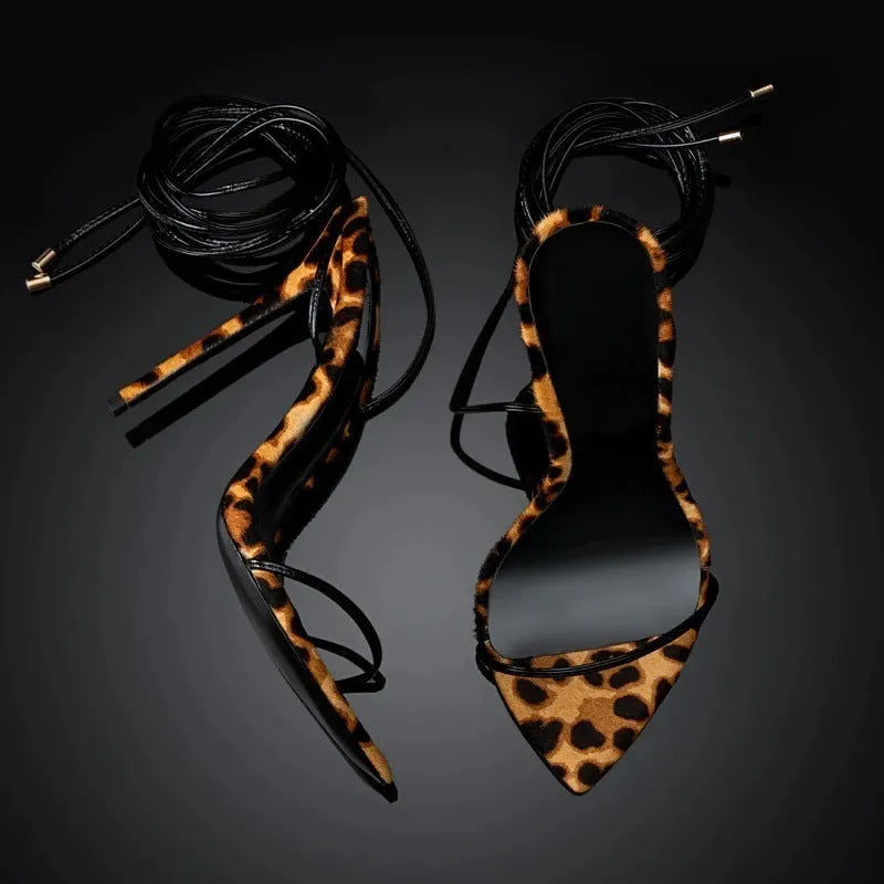 Leopard print women's Roman sandals with pointed toe, lace-up ankle strap, and buckle closure.