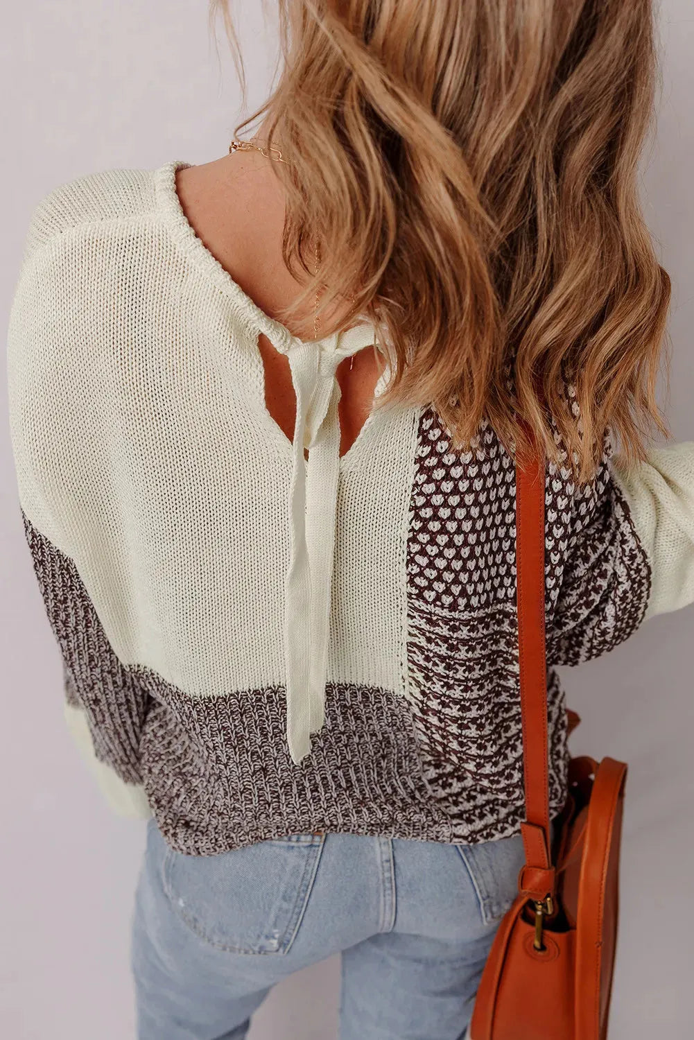 Dark khaki loose sweater with colour block design and back tie, on a model.