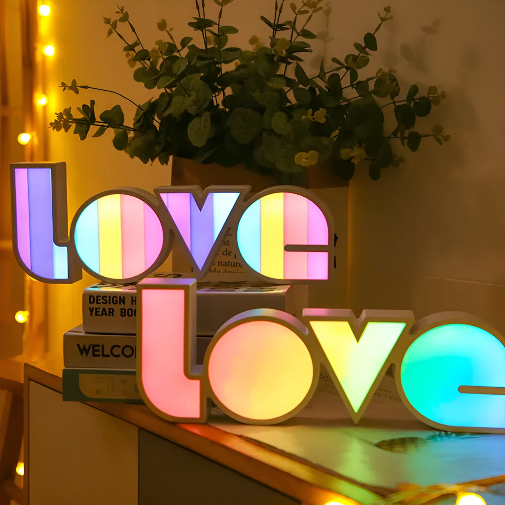 Colourful LED LOVE light decoration with rainbow lampshade on a table.