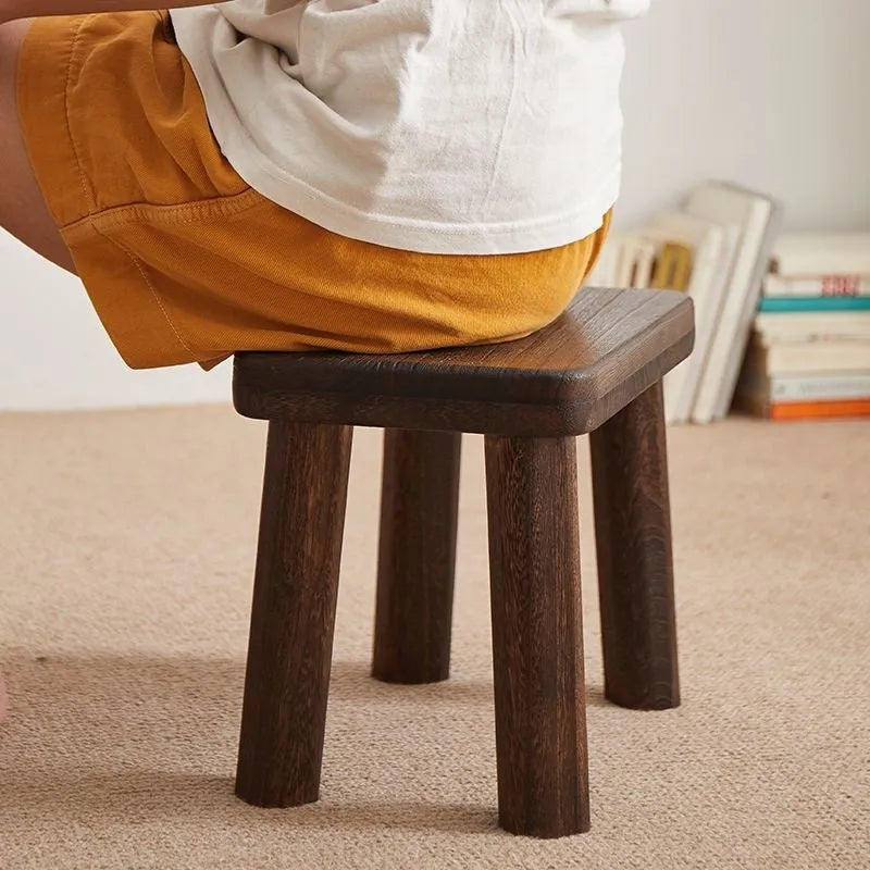Distressed wooden shoe changing stool with bracket construction in living room setting