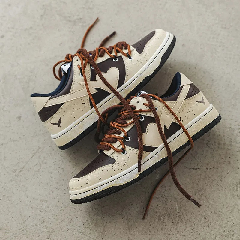 Brown low-top unisex casual sneakers with leather stitching, rubber sole, and front lace-up