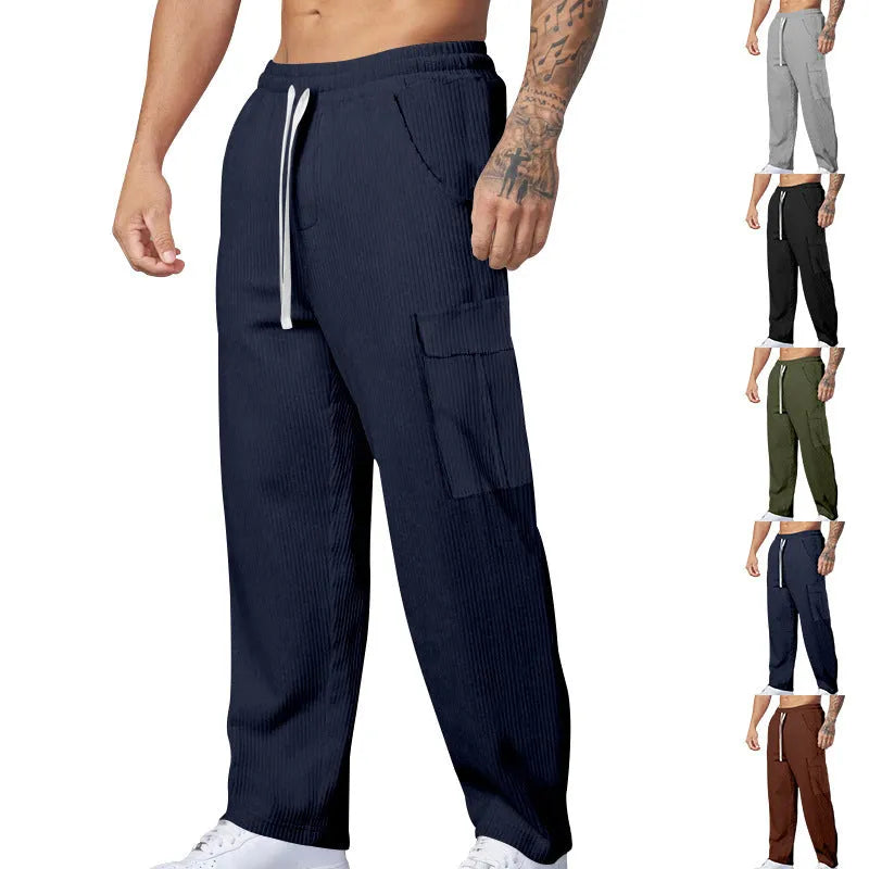 Man wearing loose-fitting straight-leg corduroy cargo trousers in navy blue with a drawstring waist.