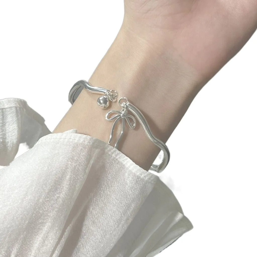 Silver adjustable bracelet with bow charm and bell opening mechanism
