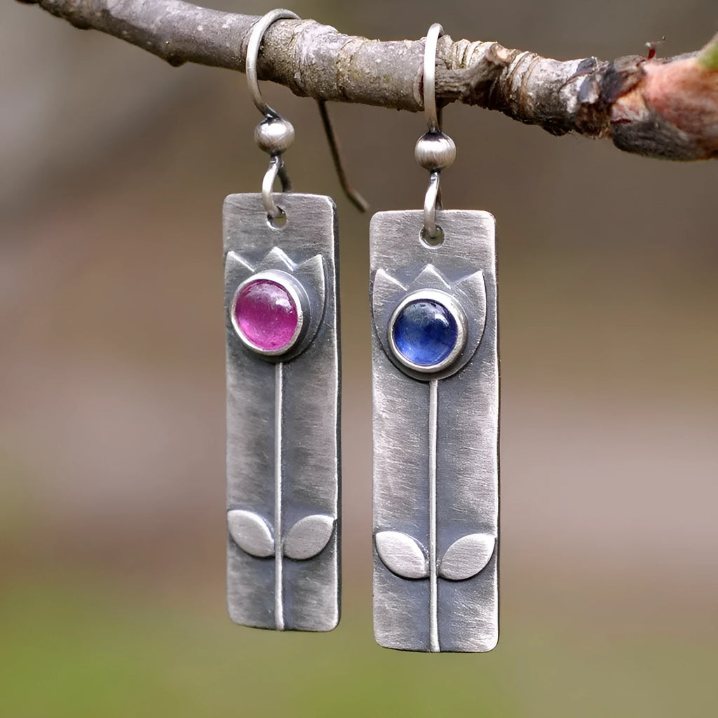 Antique finish red sapphire earrings with geometric shape and elliptical gemstone elements on metal background