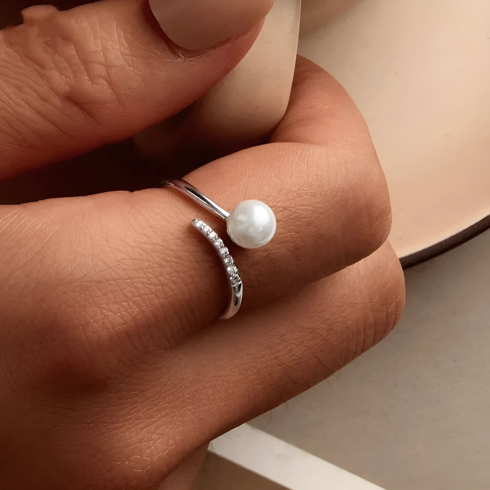 Adjustable sterling silver ring with a white shell pearl centre on an open loop band.