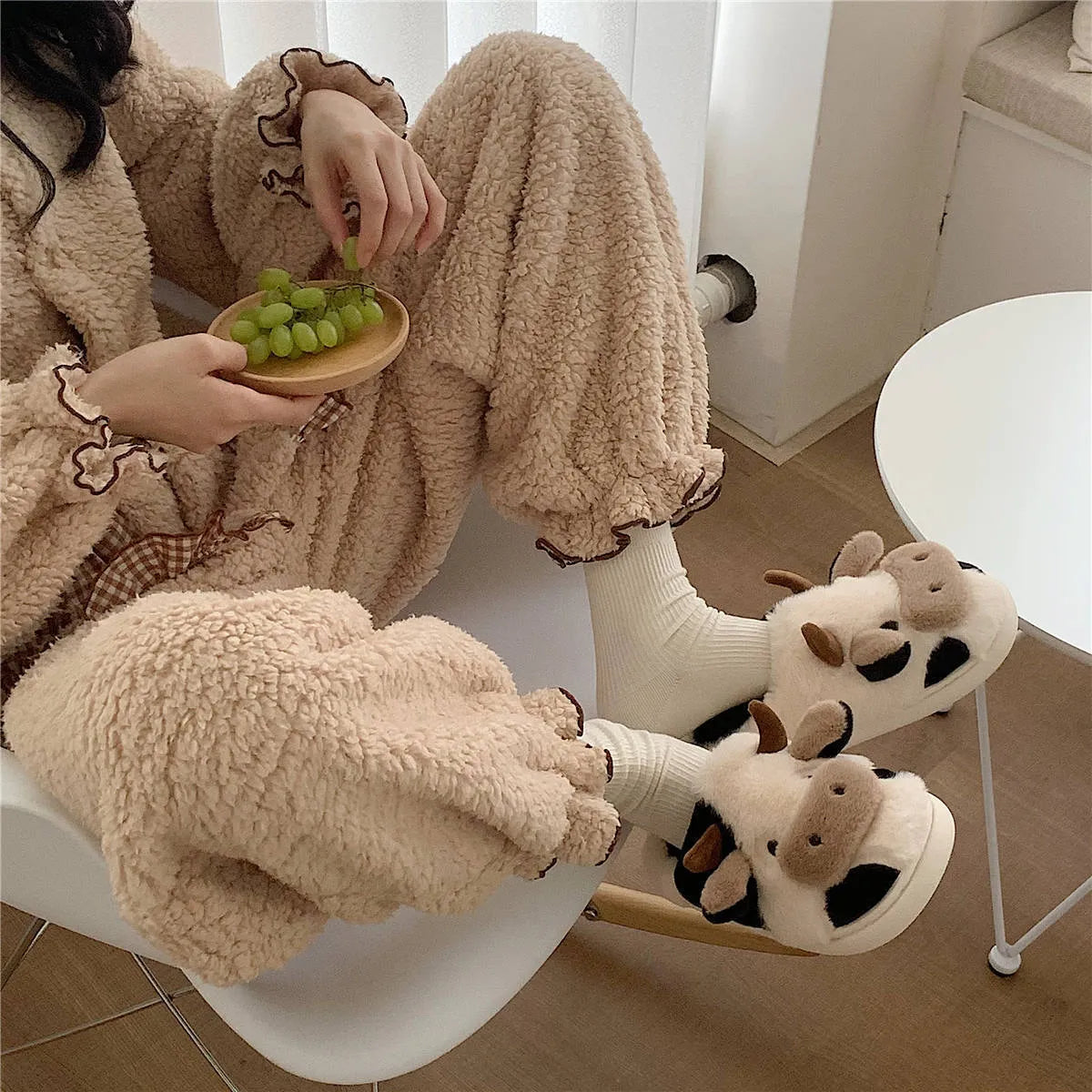 White cartoon cow slippers with plush faux fur and a textured non-slip sole.