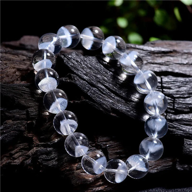 Women's white crystal pyramid bracelet with Ruyi symbols on wrist, showing ground bead texture.