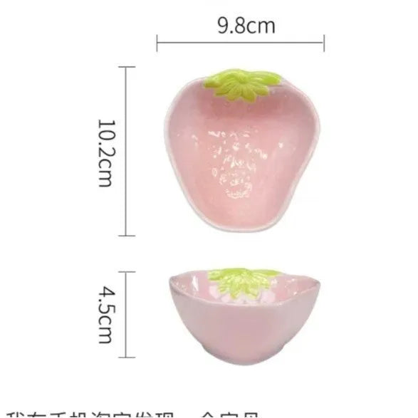 Cute strawberry pattern porcelain dinnerware set with plates, flower bowls, and a twist spoon on a table.