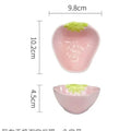 Cute strawberry pattern porcelain dinnerware set with plates, flower bowls, and a twist spoon on a table.