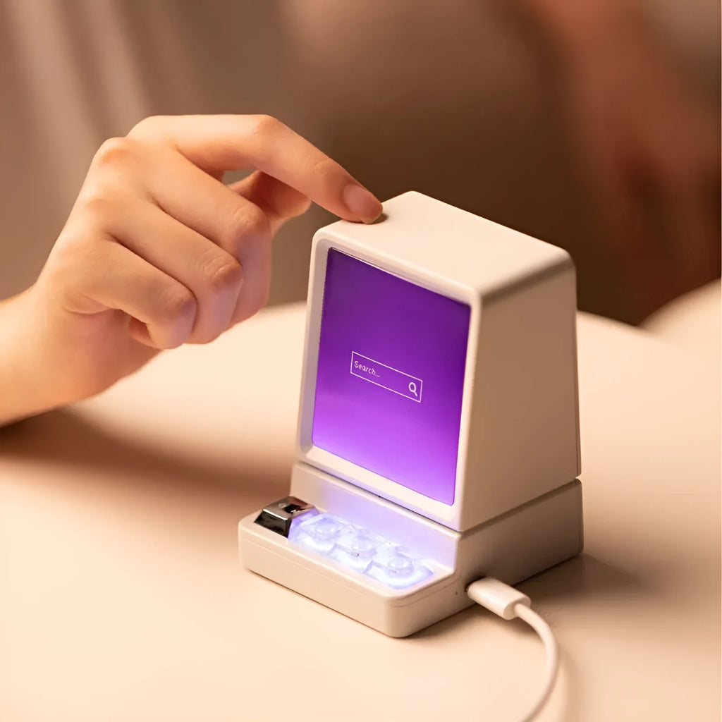 Light grey portable Bluetooth speaker shaped like a classic computer on a desk