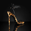 Leopard print women's Roman sandals with pointed toe, lace-up ankle strap, and buckle closure.