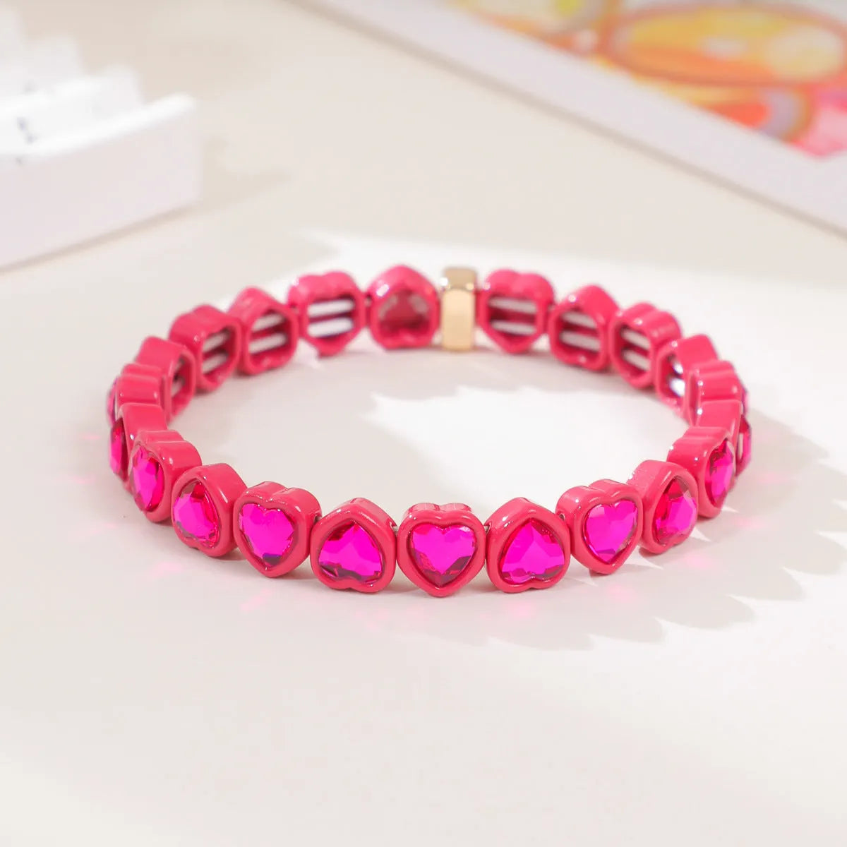 Colourful enamel finish alloy heart charm on a black stretch bracelet band.