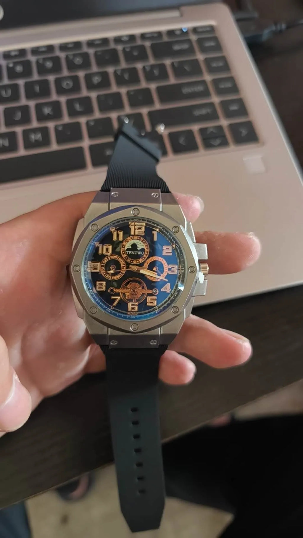 Four-ring Black And Silver Watch on a surface showing round black dial and interlocking metal bracelet