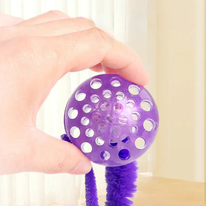 Interactive cat ball toy with elastic worm tail in green colour on wooden floor
