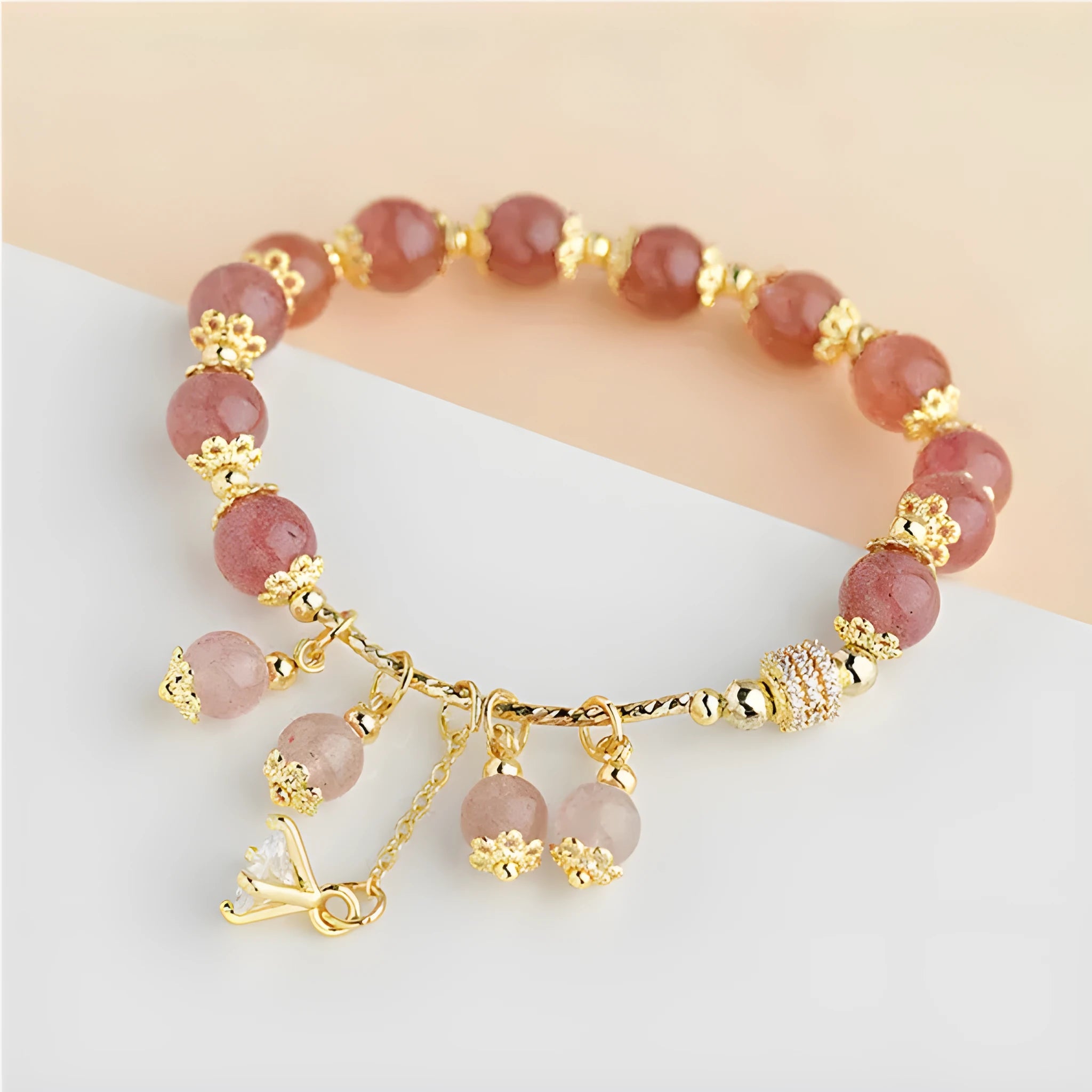Close-up of a women's pink strawberry quartz crystal bracelet with heart-shaped beads and pearl accents.