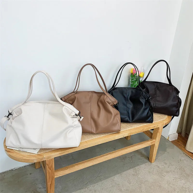 Soft black casual messenger tote bag with zip, showing internal phone pocket and adjustable long shoulder strap.