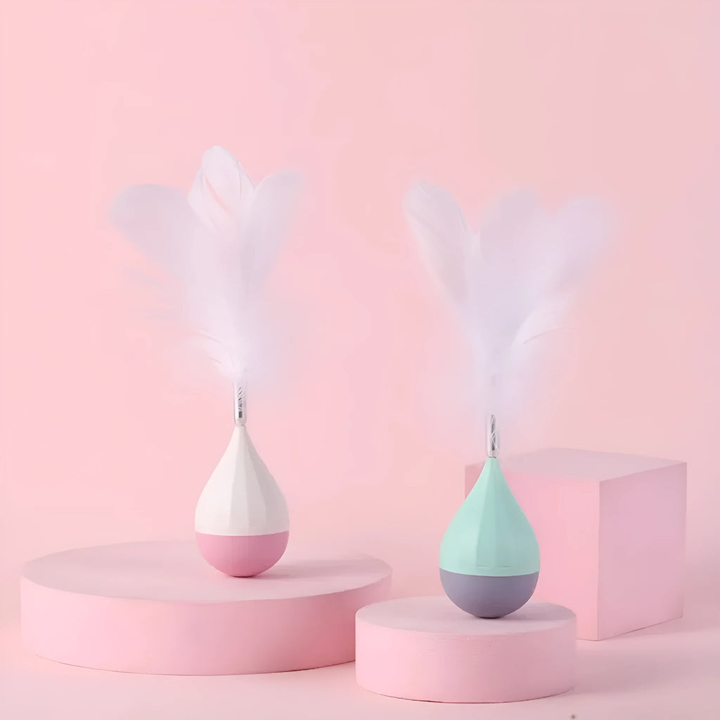 Green feather tumbler cat toy with goose feathers and aluminium alloy components on wooden floor